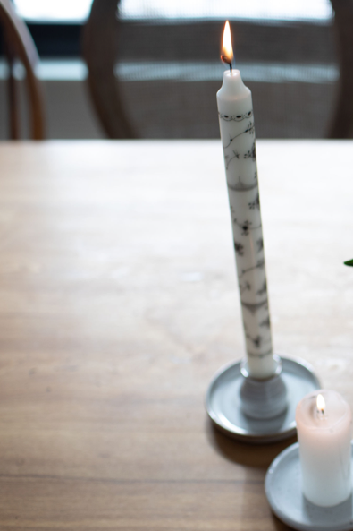 Authentic Royal Copenhagen decorative taper burning candles in black paired with a clay candle holder.