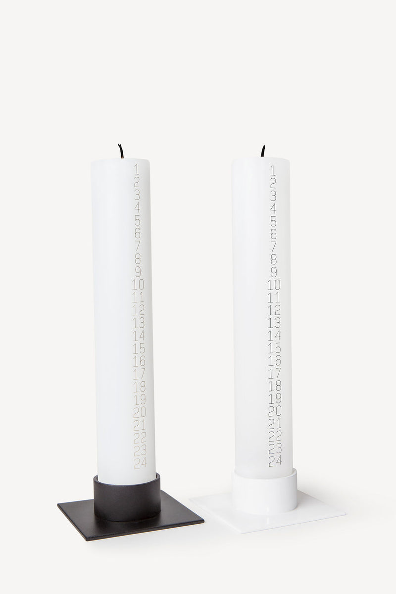 Traditional Danish Christmas countdown pillar candle with black or gold numbers for holidays and gifts shown with candle holder